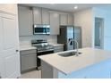 Modern kitchen with stainless steel appliances, gray cabinets, and a central island with a sink at 2739 San Marco Way, Winter Haven, FL 33884