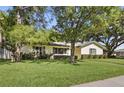 Single-story home with lush green lawn and mature trees, offering shade and curb appeal at 5334 Cypress Dr, Winter Park, FL 32792