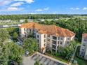Exterior shot of a multi-story condo building with a red tile roof surrounded by green trees and a parking lot at 8020 Tuscany Way # 6301, Davenport, FL 33896
