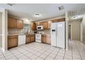 Functional kitchen with white appliances, wood cabinetry, and easy-to-clean tile flooring, ideal for Gathering meals at 830 N Sunset Dr, Mount Dora, FL 32757