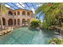 Luxurious pool area with a screened enclosure, rock waterfall, and lush tropical plants at 9400 Laws Road, Clermont, FL 34714