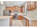 Modern kitchen features stainless steel appliances, wooden cabinets, tile backsplash, and a sink at 1246 Payne Stewart Dr, Davenport, FL 33896