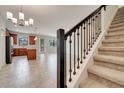 Open-concept living room with tile floors and a staircase featuring carpeted steps and black metal railings at 1246 Payne Stewart Dr, Davenport, FL 33896