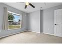 This simple, carpeted bedroom has a large window with curtains, and neutral walls at 135 Inconnu Ct, Kissimmee, FL 34759
