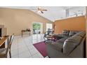 Spacious living room featuring tile flooring, a vaulted ceiling with ceiling fan and sliding glass doors to the lanai at 1803 Tillstream Dr, Orlando, FL 32818