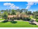 Beautiful home featuring a terracotta roof, arched windows, mature trees and lush landscaping at 3130 Butler Bay N Dr, Windermere, FL 34786