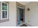 Home entryway featuring a blue front door, sidelight window, and covered porch with exterior light fixture at 413 Pursley Dr, Deland, FL 32724