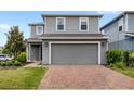 Two-story gray home featuring a brick-paved driveway, lawn, and garage door at 4301 Creek Bank Dr, Kissimmee, FL 34744
