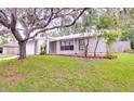 Landscaped home exterior featuring a neutral color scheme, well-maintained lawn, and a mature tree at 452 Sundown Trl, Casselberry, FL 32707