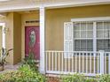 Close-up of a red front door, white porch railing and cream colored exterior at 7939 Riffle Ln, Orlando, FL 32818