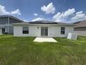 Back exterior of home, showcasing a concrete patio and solar panels at 873 Daring Dr, Davenport, FL 33837