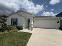 Charming single-story home with a well-manicured lawn, blue door, and two car garage at 873 Daring Dr, Davenport, FL 33837