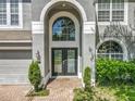 Close-up of a home's front entrance, showcasing the arched entryway, double doors, and manicured landscaping at 9454 Candice Ct, Orlando, FL 32832