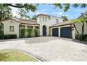 Elegant Mediterranean home with a red tile roof, striking blue garage doors, and brick paved driveway at 9809 Covent Garden Dr # Drive, Orlando, FL 32827