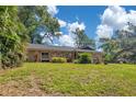 Well-maintained single Gathering house featuring attractive lawn and lush, mature trees on a sunny day at 1200 Ridge Rd, Longwood, FL 32750