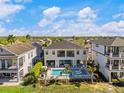 Aerial view of a beautiful backyard with a sparkling pool, palm trees, and ample seating areas for entertaining at 1526 Euston Dr, Reunion, FL 34747