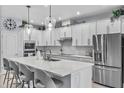 Modern kitchen with stainless steel appliances, white cabinetry, a large island with seating, and pendant lighting at 17676 Passionflower Cir, Clermont, FL 34714