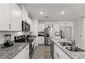 Modern kitchen features white cabinets, stainless appliances, granite countertops, and a functional island at 1792 Bull Hill Rd, Kissimmee, FL 34744
