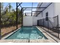 Private screened-in pool with clear blue water, surrounded by lush landscaping and a stylish patio area at 312 Famagusta Dr, Davenport, FL 33896