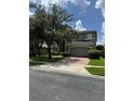 Home with a two-car garage, green lawn and large trees in a suburban neighborhood at 5040 Rock Rose Loop, Sanford, FL 32771