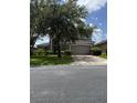 Home with a two-car garage, green lawn and large trees in a suburban neighborhood at 5040 Rock Rose Loop, Sanford, FL 32771