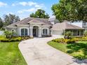 Well-manicured front exterior of a gray single-story home featuring a long driveway and lush landscaping at 8122 Westminster Abbey Blvd, Orlando, FL 32835