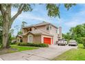 Charming two-story home with a well-manicured lawn, mature trees, and a vibrant red garage door at 9285 Wickham Way, Orlando, FL 32836