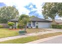 Landscaped front yard featuring a well-manicured lawn with mulch beds, bushes, and a two car garage at 1005 Black Willow Dr, Oviedo, FL 32765