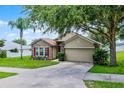 Charming one-story home with stone accents, manicured lawn, mature trees, and two-car garage at 1112 Spruce Ridge Ct, Minneola, FL 34715