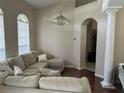 Inviting living room features a plush sectional sofa, elegant chandelier, and arched doorway at 13000 Sandy Pine Ln, Clermont, FL 34711