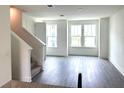 Bright living room with hardwood floors, three large windows, and staircase leading to upper level at 15119 Grove Lake Dr, Winter Garden, FL 34787