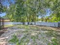 Large, fenced backyard with a gravel and grassy area, mature trees, and storage shed at 2109 Hartwell Ave, Sanford, FL 32771