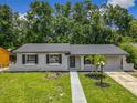 An updated single-story house featuring a nice lawn, fresh paint and trim, and mature shade trees at 2109 Hartwell Ave, Sanford, FL 32771