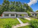 Inviting single-story home with lush green lawn, a walkway, and mature trees at 2109 Hartwell Ave, Sanford, FL 32771