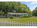 Inviting single-story house with a screened porch, manicured lawn and a partial white picket fence at 224 Woodmere Blvd, Sanford, FL 32773