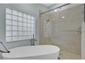 Luxurious bathroom featuring soaking tub, a glass shower with marble tiles and a unique glass block window at 2250 Blossomwood Dr, Oviedo, FL 32765