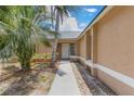 Front entrance to a tan home with a white door, leading up a sidewalk bordered with landscaping at 2838 Maldive Ct, Deltona, FL 32738