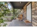 Covered front porch showcasing stone facade, flowering vines and a rocking chair at 369 Bluff Lake Rd, Mascotte, FL 34753