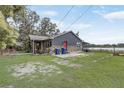 View of the home's exterior featuring a stone facade, red door, and a lovely lakeside view at 369 Bluff Lake Rd, Mascotte, FL 34753
