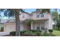 Inviting two-story home featuring a landscaped front yard with a palm tree and lush green bushes at 844 Suffolk Pl, Davenport, FL 33896