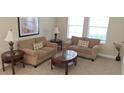 Cozy living room featuring comfortable sofas, wooden tables, and natural light from the window at 844 Suffolk Pl, Davenport, FL 33896