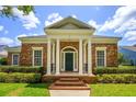 Inviting brick home with a columned entrance, green door, and beautifully maintained landscaping at 922 Jasmine St, Celebration, FL 34747
