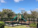 Community playground with slides, climbing structures, benches, and a secure fenced perimeter for safety at 1003 E 10 St, Apopka, FL 32703