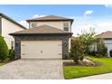 Two-story home with a neutral color palette, stone accents, and a two-car garage, complemented by lush landscaping at 1409 Bellamy Dr, Reunion, FL 34747