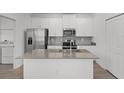 Bright kitchen with white cabinetry, stainless steel appliances, and center island for food preparation at 2563 Relaxing Ln, Kissimmee, FL 34744