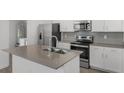 Modern kitchen features stainless steel appliances, grey backsplash, and center island with sink at 2563 Relaxing Ln, Kissimmee, FL 34744