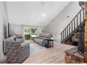 Bright living room with vaulted ceiling, light wood floors, comfortable seating, and a sliding glass door to the patio at 264 Agnes Ave, Longwood, FL 32750