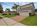 Charming two-story house featuring a lush lawn, two-car garage, and beautiful landscaping with mature palm trees at 3472 Gretchen Dr, Ocoee, FL 34761