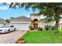 Charming single-Gathering home showcasing a well-manicured lawn, brick driveway, and white car at 501 Lake Cummings Way, Lake Alfred, FL 33850