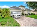 Charming single-Gathering home showcasing a well-manicured lawn, brick driveway, and white car at 501 Lake Cummings Way, Lake Alfred, FL 33850